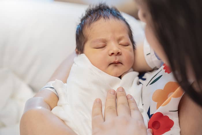 Closeup portrait of young asian Indian mother holding newborn baby 